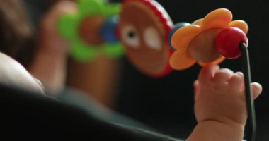 Baby hands playing with toy inside chair crib