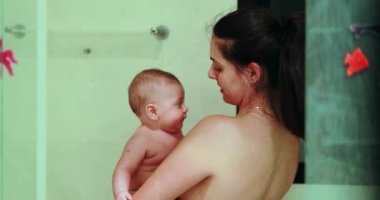 Mother with baby newborn inside shower bathing and bonding together