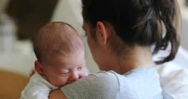 Mother holding newborn baby tapping in the back