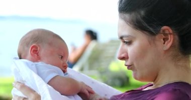 Mother interaction with newborn baby outdoors showing care and love