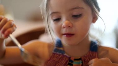 Portrait of little girl eating lunch smiling candid