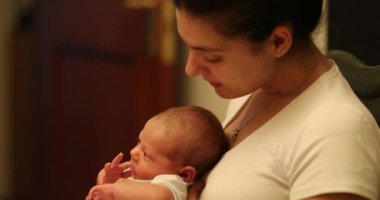 Mother holding newborn baby infant kissing showing love affection care