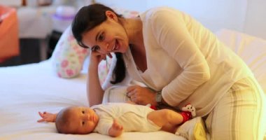 Candid happy mom with newborn baby in bedroom