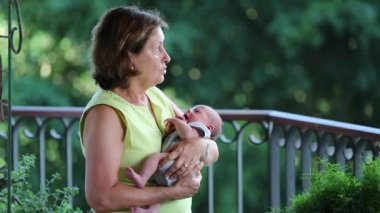 Candid grand-mother holding baby grand-son outdoors