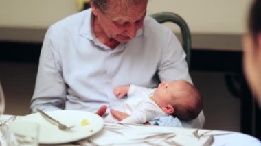 Grand father holding newborn baby grandson interaction candid family moment