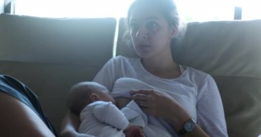 Casual candid Mother breastfeeding newborn baby infant at home
