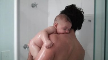 Father holding baby son shower bathing and washing