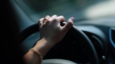 Closeup girl hand holding steering wheel driving on road with one hand