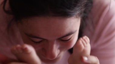 Mother playing with baby feet, covering face with foot peekaboo