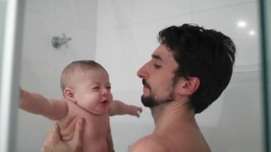 Father holding baby in the shower bathing and washing, dad bonding with baby son, real life
