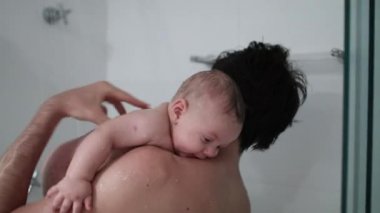 Father holding baby in the shower bathing and washing, dad bonding with baby son, real life