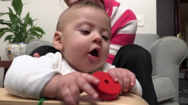 Adorable baby putting toy object in mouth and then falling down