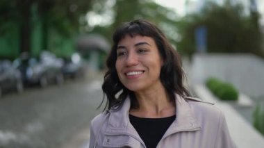Happy young woman walking outside. One confident hispanic Brazilian girl walks outdoors in street smiling