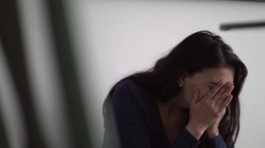 Hopeless woman covering face in shame and regret feeling emotional anguish sitting on floor at home suffering alone