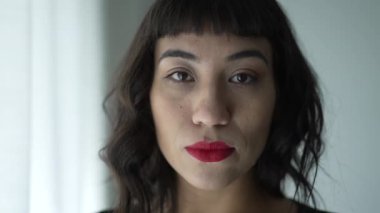 One South American woman with serious expression portrait face wearing red lipstick looking at camera