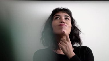 Portrait of a hispanic latina thinking of a creative idea. One South American girl daydreaming solution