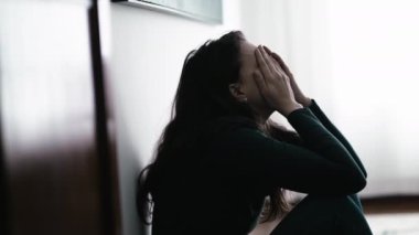 One desperate person suffering alone covering face with shame sitting on floor at home. Woman in emotional pain