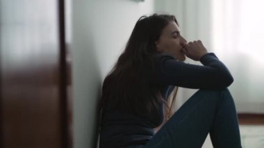 Anxious woman sitting on floor suffering from mental illness at home. Lonely person feeling despair and hopelessness