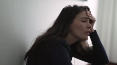 Nervous woman suffering from depression sitting on floor. Frustrated person in mental anguish feeling regret