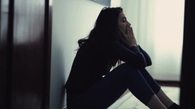 Desperate person in distress during emotional crisis. Woman sitting on floor at home feeling ashamed. Depressed girl alone