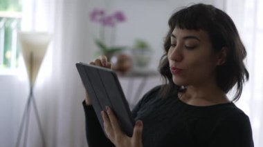 Happy woman browsing internet on tablet. One hispanic girl choosing item online deciding what to buy or touch