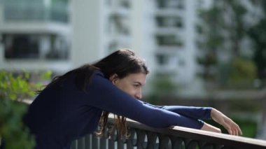 Relaxed young woman stretching body standing at balcony apartment smiling feeling happy