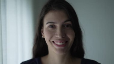 Portrait of a smiling woman in her 30s standing by window. Closeup happy person face