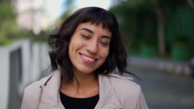 Smiling happy young woman walking outside. Portrait face of one hispanic latina girl walks smiling