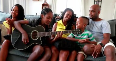 Sıradan siyahi Afrikalı aile gitarla bağ kuruyor. Kızım müzik aleti çalıyor.