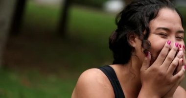 Two friends laughing and smiling outside. Interracial friendship, hispanic and african women
