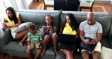 African familt using technology at home sofa