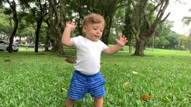 Baby toddler walking outside on grass. Cute infant steps staying in balance