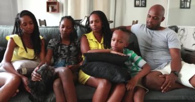 Sıradan bir Afrikalı aile evde oturma odasında oturuyor. Siyahi aileler ve çocuklar kanepede yan yana.