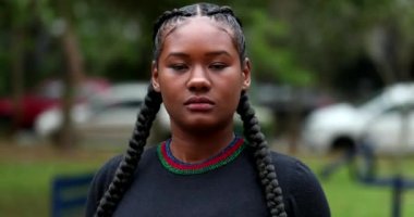 Young black African woman face, tracking shot of mixed race ethnicity girl standing outside at park