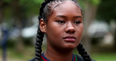 Confident African woman standing outside, tracking shot of black girl looking at camera