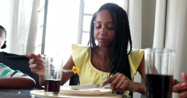 Happy black girl at lunch table. Smiling African woman with family