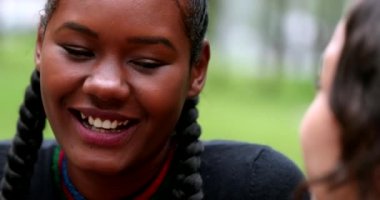 African young woman laughing and smiling outside with friend