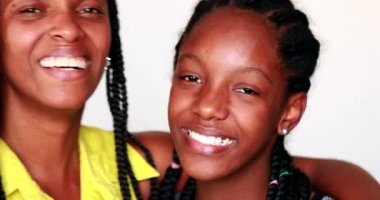 Afrikalı anne ve genç kız kameraya gülümsüyor birlikte poz veriyorlar.