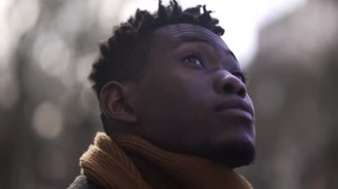 Contemplative African young man face looking up at the sky