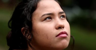 Latina girl looking at sky smiling. Hispanic young woman close-up face with HOPE and FAITH