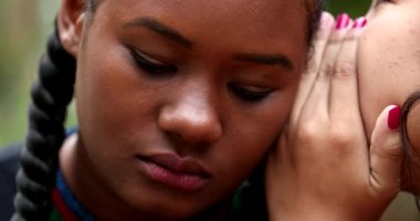 Friend sharing gossip secret to girl ear, surprise shocking reaction