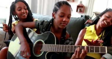 Sıradan siyahi Afrikalı aile gitarla bağ kuruyor. Kızım müzik aleti çalıyor. 