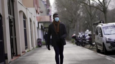 Elegant African man walking in slow-motion wearing face mask prevention against pandemic