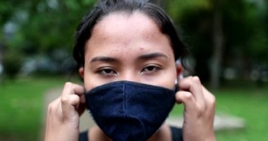 Woman removing face mask, happy hispanic girl taking off covid-19 face mask, end of pandemic concept