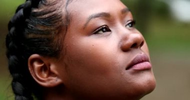 African woman in 20s face looking up to sky. Black ethnicity girl with HOPE
