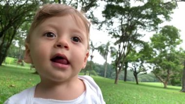Adorable baby standing outside observing and falling to ground
