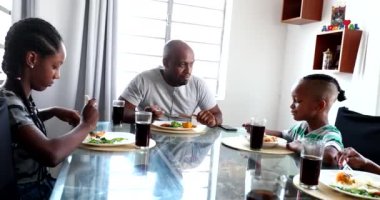 Black family at lunch interaction. African mixed race father and children together during meal