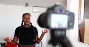 Young woman vlogging in front of camera tripod
