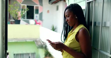 Black woman typing message on smartphone device at home