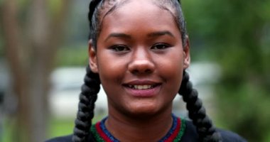 Portrait African young woman in 20s standing outside at park smiling